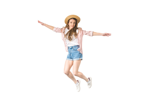 glücklich Mädchen mit Hut springt mit offenen Armen und lächelt in die Kamera isoliert auf weiß - Foto, Bild