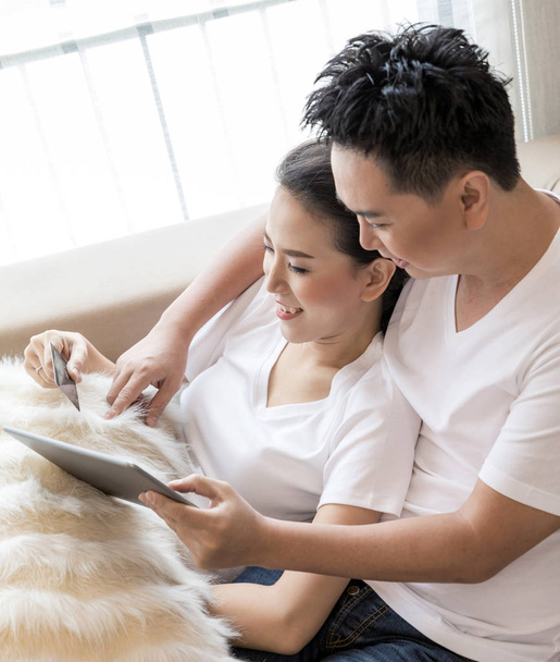 Genç çift için modern yaşam tarzı ve e-ticaret kavramı çağdaş evin oturma odasında kredi kartıyla alışveriş için tablet kullanma - Fotoğraf, Görsel