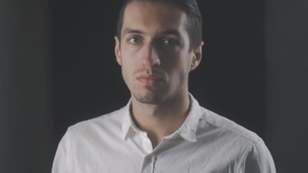 Portrét mladé atraktivní muž v bílé košili, při pohledu na fotoaparát - Záběry, video