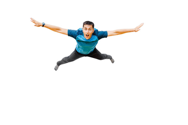 verrast jonge man vliegt in wijd gescheiden handen geïsoleerd op wit. Concept fitness of trampoline centrum - Foto, afbeelding