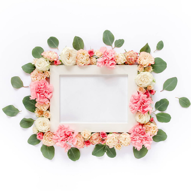 White frame decorated with pink roses flowers and leaves of eucalyptus. Flat lay, top view. Floral background. Floral frame. Frame of flowers. - Zdjęcie, obraz