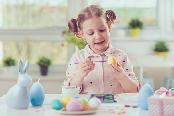 Happy pretty child girl having fun during painting eggs for east - Foto, imagen