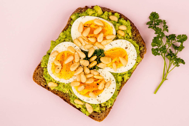 Çam fıstığı ve çavdar ekmeği açık sandviç ezilmiş avokado haşlanmış yumurta - Fotoğraf, Görsel