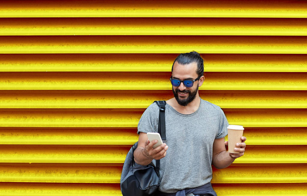 man with coffee cup and smartphone over wall - Foto, Bild