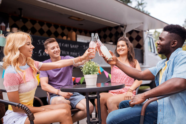 friends clinking bottles with drinks at food truck - Photo, Image