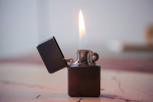 lighter with flame on wooden table - Photo, Image