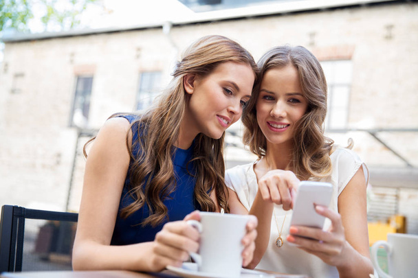 young women with smartphone and coffee at cafe - Photo, Image