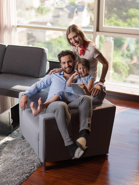 Glückliche junge Familie spielt mit Tablet zu Hause auf dem Sofa - Foto, Bild