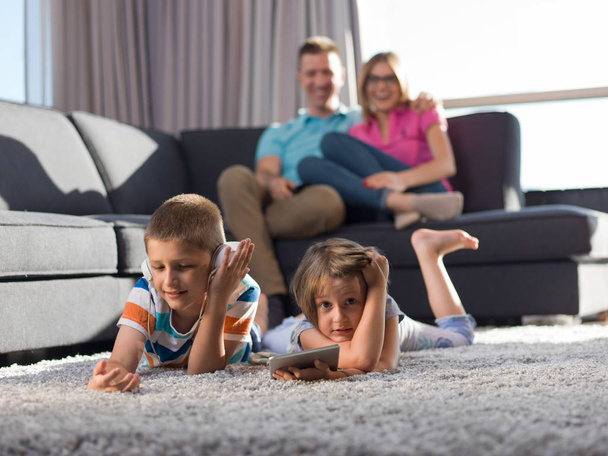Familia joven feliz jugando juntos en casa.kids usando la tableta en el suelo - Foto, imagen