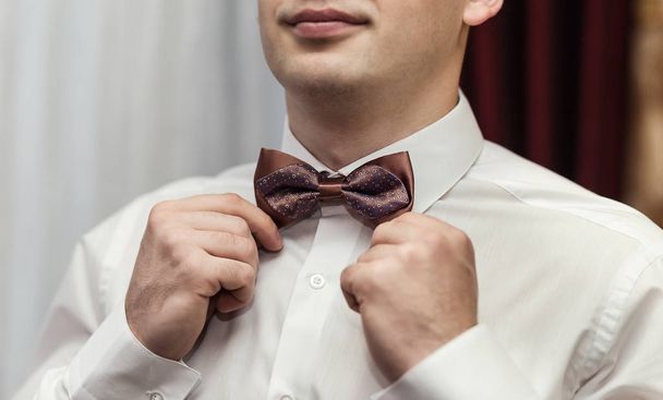hombre de negocios que se pone corbata de lazo, ropa de mariposa hombre, novio preparándose en la mañana antes de la ceremonia de boda
 - Foto, Imagen