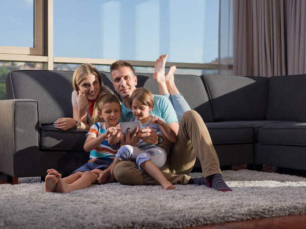 Happy Young Family Παίζοντας μαζί με tablet στο σπίτι κάθεται στον καναπέ - Φωτογραφία, εικόνα