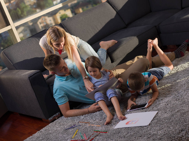 Happy Young Family Playing Together at home using a tablet and a children's drawing set - Foto, Imagem
