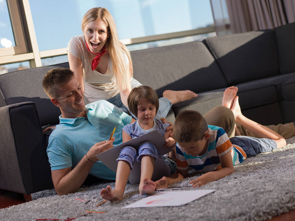 glückliche junge Familie, die zu Hause mit Tablet und Kinderzeichenset zusammen spielt - Foto, Bild