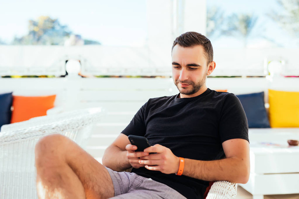 Pohledný muž relaxační tuping na telefonu na pláži. Letní povolání - Fotografie, Obrázek