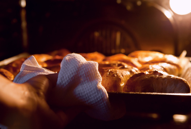 Woman hand taken out apple pies from the oven - Фото, изображение