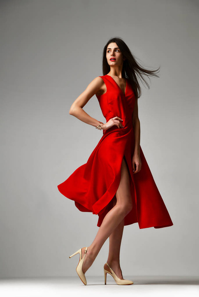 Pretty brunette woman in formal red dress stiletto heels shoes - Fotó, kép