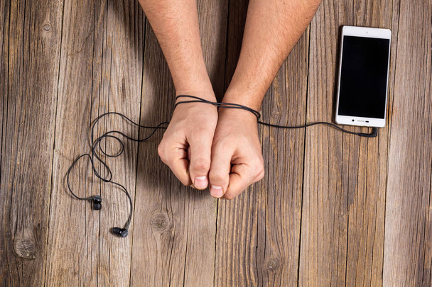 hands of man tied with phone headset, as the concept of man's dependence on music, technology. - Photo, Image