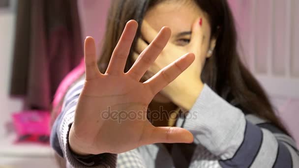 Mujer joven asustada por la violencia doméstica primer plano de la mano frente a la cara
 - Metraje, vídeo