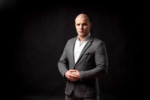 Young bald man in gray suit and white shirt posing on black isolated background - Photo, Image