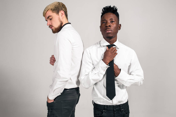 Friends. Two guys in white shirts and dark pants posing in the studio on a white background - Zdjęcie, obraz