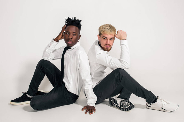 Friends. Two guys in white shirts and dark pants posing in the studio on a white background - Photo, image