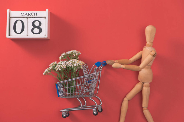 Shopping trolley with flowers on red background. Woman Day shopping and sale. - Foto, Imagem