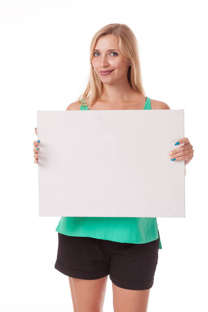 Blonde with long hair posing with white plate. Put a logo, advertisement. Photo on a white background for advertising. shows different postures and emotions. Posing with nameplate on a white background. dressed in a business black suit. skirt  - Фото, изображение