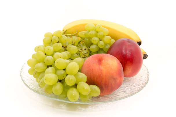 Bananen, druiven, perziken, nectarines, op een bord - Foto, afbeelding