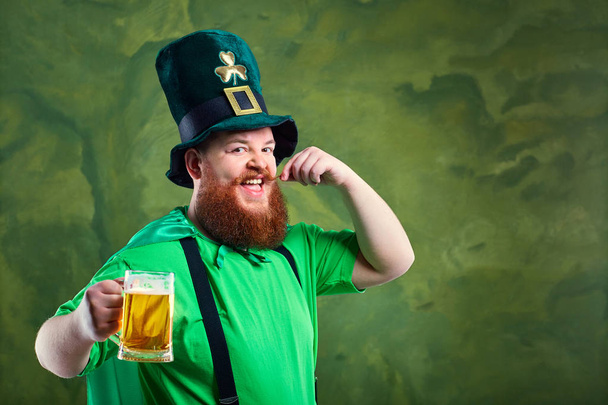 A fat man with a beard in St. Patricks suit is smiling with a m - Fotoğraf, Görsel