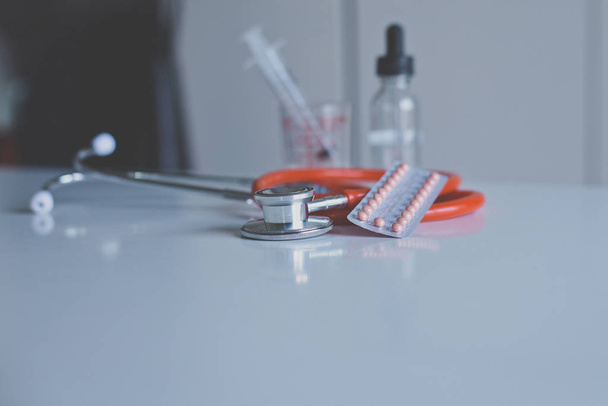 Стетоскоп красный цвет с противозачаточными таблетками на рабочем столе, здравоохранение и медицинская концепция
 - Фото, изображение