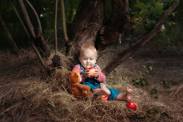 Child girl sits under a tree. - Φωτογραφία, εικόνα