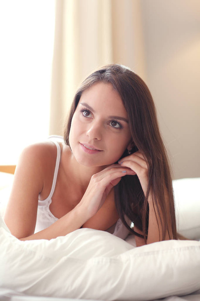 Beautiful brunette lying on bed at home - Фото, зображення