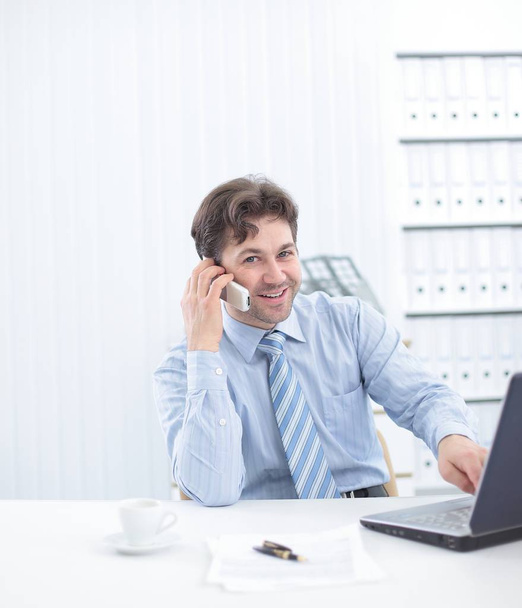 handsome businessman sitting at Desk and talking on a cell phone - Foto, immagini