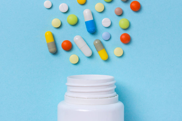 Surtido de píldoras de medicamentos farmacéuticos, tabletas y cápsulas y frasco sobre fondo azul
 - Foto, Imagen