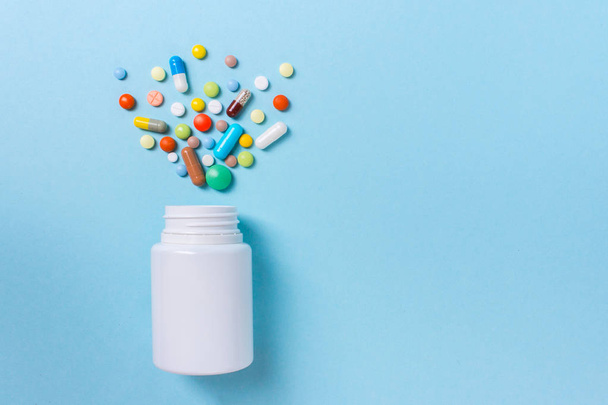 Geassorteerde farmaceutische geneeskunde pillen, tabletten en capsules en fles op blauwe achtergrond. Ruimte voor tekst kopiëren. - Foto, afbeelding