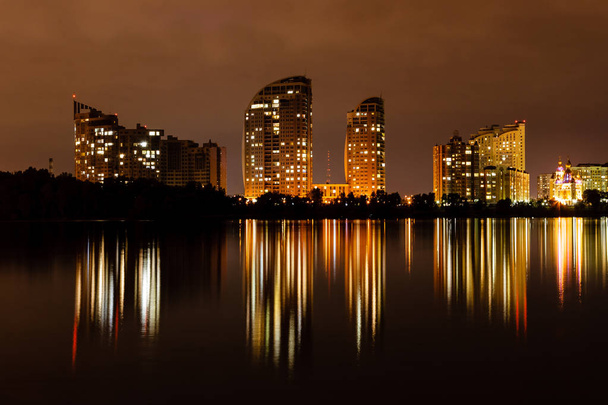 cidade noturna com reflexo de casas no rio
 - Foto, Imagem