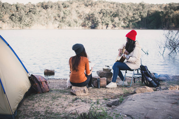 Happy Asian women playing guitar in nature winter season,Relax time on holiday concept travel and camping partnership,selective and soft focus,tone of hipster style - Photo, image