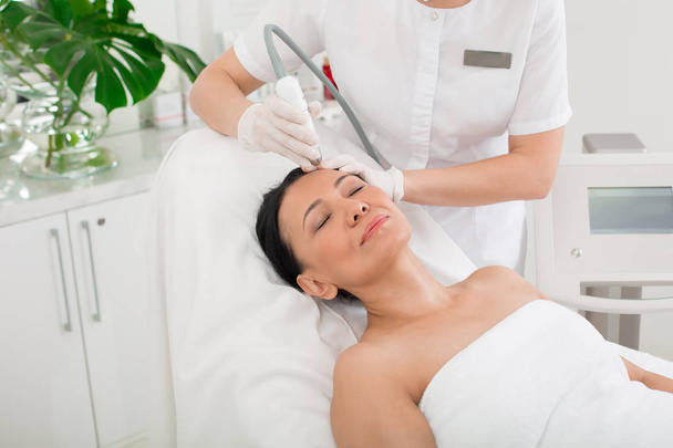 Relaxed woman going for laser treatment in beauty salon - Zdjęcie, obraz