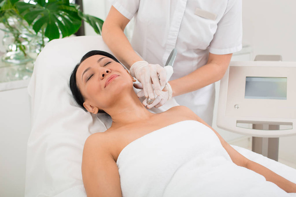Glad woman taking procedure in wellness center - Photo, Image