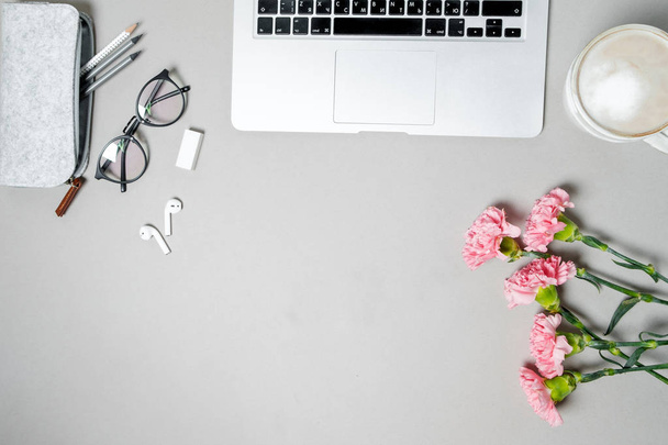 Escritorio de oficina de mujer laica plana. Espacio de trabajo con portátil, clavel rosa, papelería sobre mesa blanca. Top vie
 - Foto, Imagen