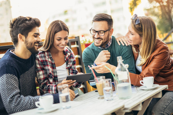 Skupina čtyř přátel se spolu baví kávou. Dvě ženy a dva muži v kavárně si povídají a baví se - Fotografie, Obrázek