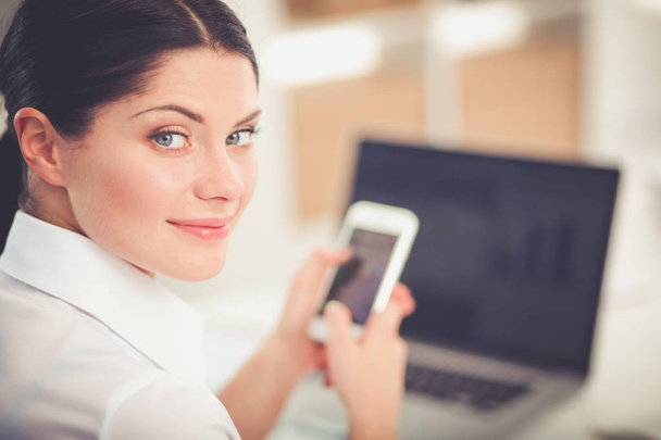 Businesswoman sending message with smartphone in office. Businesswoman - Photo, image