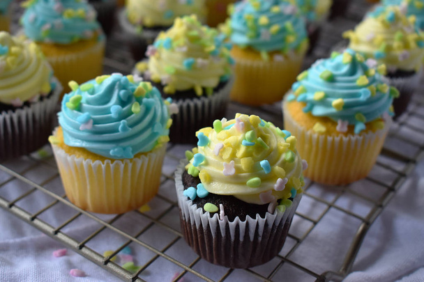 Cupcakes azuis e amarelos em assadeira com polvilhas de primavera
 - Foto, Imagem