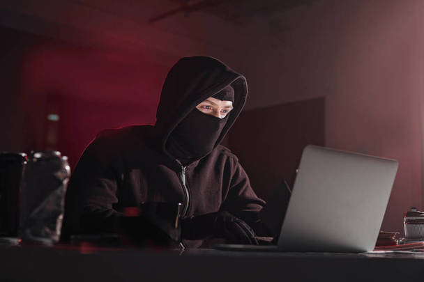 Serious computer fraudster noting in laptop - Foto, imagen
