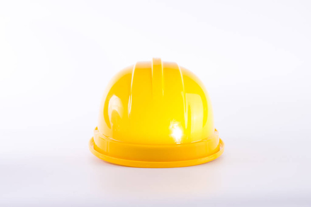 白い背景の上の黄色の安全ヘルメット。ヘルメットは白で隔離。安全装置のコンセプト。労働者と産業のテーマ. - 写真・画像