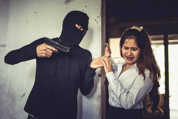 Розбійник змушує жінку вкрасти своє золоте намисто ручним пістолетом у кутку будівлі. Страх перед жінками під час зустрічі з злодіями. Кримінальна концепція кримінального сексуального та нелегального насильства
 - Фото, зображення