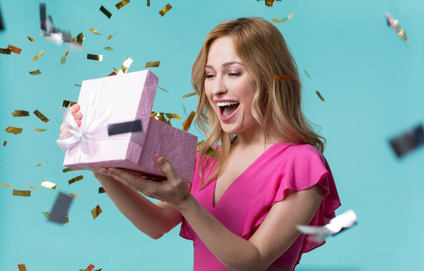 Cheerful girl opening gift box with interest - Foto, Imagem