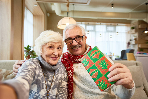 Portrait de heureux couple de personnes âgées tenant la caméra et prenant des photos selfie sur Cristmas ou enregistrement vidéo massage
 - Photo, image
