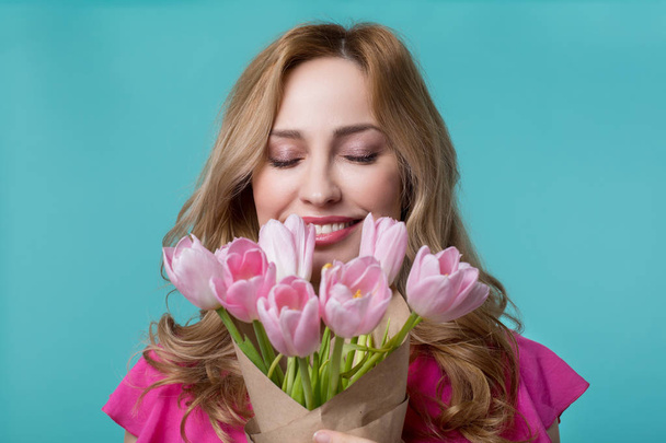 Happy young woman enjoying scent of tulips - Foto, afbeelding
