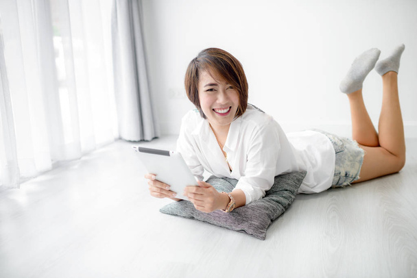 Beautiful young asian woman wearing white shirt and using tablet - Foto, imagen
